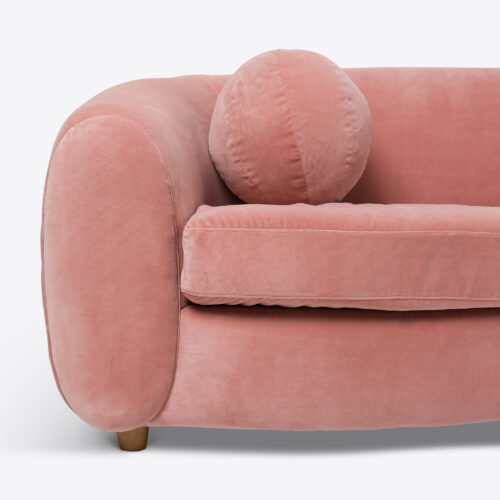 curved sofa in pink velvet with pink ball cushion