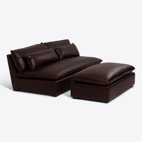 dark brown leather armless sofa with oblong leather bolster cushions