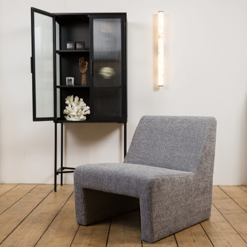 grey boucle armless chair with alabaster wall light and tall drinks cabinet in black